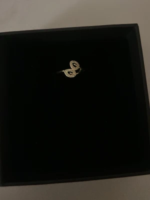 Guldfärgad ring - Snygg guldfärgad ring i form av en orm som slingrar sig runt fingret. Ringen har en detaljrik yta som ger ett lyxigt intryck och passar perfekt för dig som gillar unika smycken. Enkel att matcha med andra accessoarer och ger en cool touch till din stil.