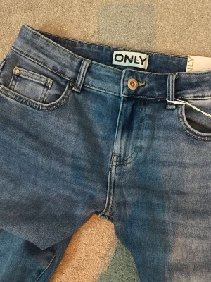 Blå jeans lågmidjade från ONLY  - Snygga blå jeans från ONLY med klassisk femficksdesign och utsvängda ben  . Helt oanvända med lappar kvar i st 27/22