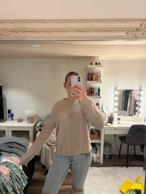 Beige stickad tröja från 157 - Beige stickad tröja från 157 med grovstickat mönster och rund halsringning. Tröjan har en avslappnad passform och långa ärmar, perfekt för lager-på-lager-stil. Mjuk och skön, passar till jeans eller kjol.