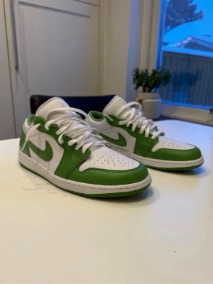 Nike Air Jordan 1 Low skor/sneakers vit/grön - Snygga Nike Air Jordan 1 Low sneakers i vitt och grönt med klassisk siluett. Skorna har vita skosnören, perforerad tåbox och gröna detaljer runt hela skon. Materialet är en mix av läder och syntet. Perfekt för dig som vill sticka ut med stilrena sneakers. Skorna är aldrig använda, endast testade. Snabb frakt, skickas samma dag😁⚡️📦