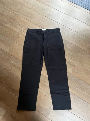 Svarta cargobyxor med raka ben - Svarta cargobyxor med raka ben och flera praktiska fickor på sidorna från H&M. Byxorna har klassisk cargomodell med knapp och dragkedja framtill. Fråga gärna vid frågor💕