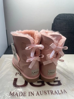 Rosa UGG boots australia bow  - Säljer ett par ljusrosa UGG boots i fårskinn pga att de inte passade den jag köpte de till. De är helt nya och har lappen kvar.