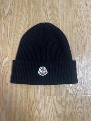 Svart Moncler mössa i ribbstickad ull - Säljer en svart ribbstickad mössa från Moncler.Ny utan prislapp och aldrig använd.