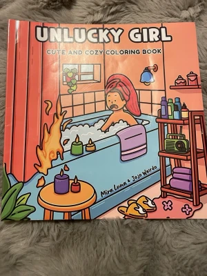 Unlucky Girl målarbok - En färgglad och rolig målarbok med titeln 'Unlucky Girl'. Omslaget är rosa med tecknad illustration av en tjej i badkar, omgiven av ljus och badrumsdetaljer. Perfekt för dig som gillar kreativa och mysiga aktiviteter.