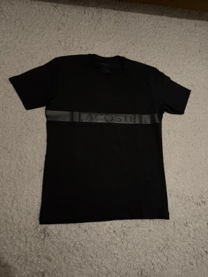 Svart Lacoste t-shirt med logoband - Helt ny aldrig använd. Storlek S