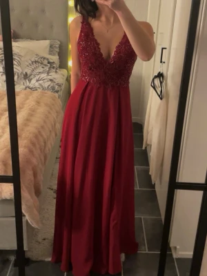 Vinröd balklänning från jjs house - Mycket fint skick och använd endast en gång på min bak i 9an, inga defekter finns. Balklänningen har en lång kjol med slits (de bild 3) och glittriga spetsdetaljer upptill