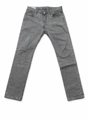 Levis 501 - Snygga grå jeans från Levi's med klassisk femficksmodell och raka ben. Jeansen har normal midja, knappgylf och är tillverkade i slitstark denim. Perfekta för en avslappnad och trendig look. Storleken är 34/34. 