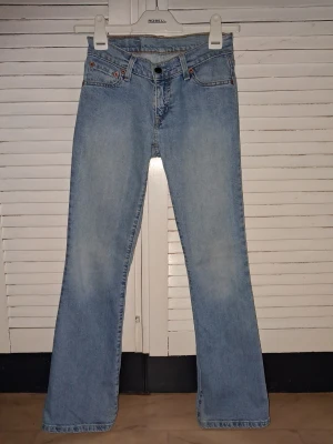 Levi's ljusblå bootcut jeans - Säljer ett par ljusblå Levi's jeans med klassisk femficksmodell och bootcut passform. Jeansen har en snygg tvättad look, hällor för skärp och Levi's ikoniska läderpatch bak i midjan. Perfekta för en avslappnad och trendig stil.