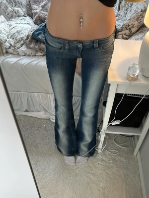 Blå bootcut jeans från Replay - Säljer ett par blå bootcut jeans från Weekday -Cheap monday- med låg midja, och snygg tvätt med ljusare partier framtill och baktill. Perfekta för en avslappnad och trendig look. Jeansen passar perfekt för mig som är 158 och har storlek xs/s. Har använts jätte fåtal gånger och bara legat i garderoben. 32 raktöver midjan som motsvarar w 27.