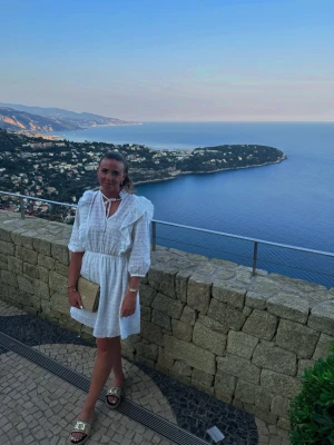 Vit kort klänning från GANT med volangdetaljer - Säljer en söt vit kort klänning med volangdetaljer och knytning i halsen. Klänningen har trekvartsärm och markerad midja, perfekt för varma dagar. Lätt och luftig, passar till sommarens alla tillfällen.