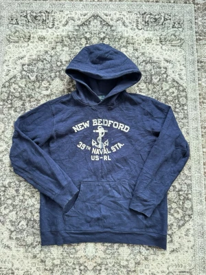 Ralph Lauren Hoodie⚓️ - Snygg Ralph Lauren hoodie med vit text och ankare på bröstet där det står 'New Bedford 39th Naval Sta. US-RL'. Klassisk känguruficka framtill och huva. För mer info är de bara att skriva! Storlek L/Xl kids, M i vanlig storlek. Pytteliten fläck vid armen som knappast syns!