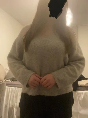 Ljusgrå stickad tröja - Mjuk och enkel ljusgrå stickad tröja med rund hals och långa ärmar. Tröjan har en rak passform och ribbstickade muddar vid ärmslut och nederkant. Perfekt att slänga på sig när det är kyligt ute.