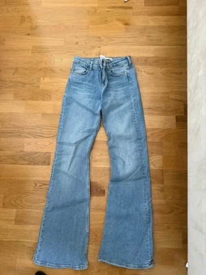 Ljusblå bootcut jeans lågmidjade  - Säljer ett par ljusblå bootcut jeans med klassisk femficksdesign och dragkedjegylf. Jeansen har utsvängda ben och är tillverkade i denim. Perfekta för en avslappnad och trendig look.
