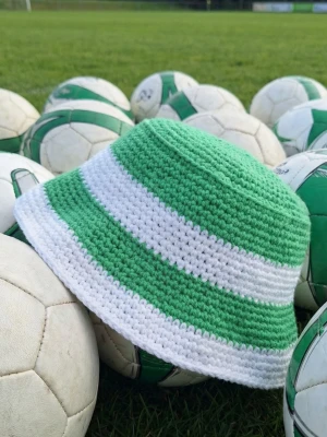 Grön och vit virkad bucket hat - Cool bucket hatt i grönt och vitt med breda ränder. Hatten är virkad I slitstarkt repgarn.  Tvättbar. Vuxen stl.