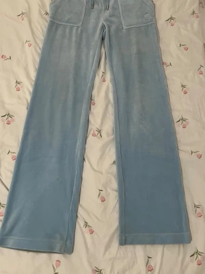 Blå velour mjukisbyxor Juicy Couture - Säljer ett par ljusblå mjukisbyxor från Juicy Couture i mjuk velour. Jag köpte dessa byxor för drygt 1 år sedan. Byxorna är använda få antal gånger och kom inte till mycket använding eftersom att de inte passar min stil. Om du har frågor så är det bara att fråga på❤️