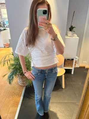 Blå bootcut jeans med fickdetaljer - Säljer ett par blå bootcut jeans med snygga fickdetaljer bak. Storlek 170. Jeansen har en lätt tvättad look och är tillverkade i denim med stretch för skön passform. Perfekta för dig som gillar stocholm stil eller bara gillar jeansen!💗💗 