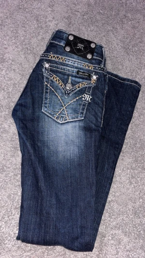Mörkblå Miss Me jeans med brodyr - Mörkblå miss me jeans med brodyr på fickorna. Låg midja. Midjan är 35 cm och innerbenslängden är 80 cm 💕 (små slitningar längst ner syns på sista bilden)
