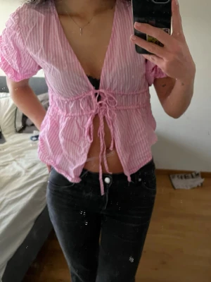 Rosa randig blus med snörning - Söt rosa och vit randig blus med korta puffärmar. Blusen har snörning framtill❤️