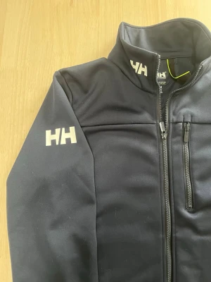 Helt Hansen fleece  - Fleece från märket Helly hansen i storlek M, mörkblå, mycket bra skick men öglan har gått av innuti fleecen, nypris 1500, skriv vid frågor!