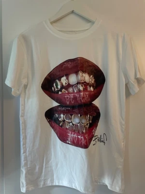 Vit t-shirt med läpp motiv - Cool vit t-shirt från shein med ett stort tryck av två läppar på framsidan. T-shirten har korta ärmar och en klassisk passform. Perfekt för dig som vill sticka ut med en unik och edgy stil.