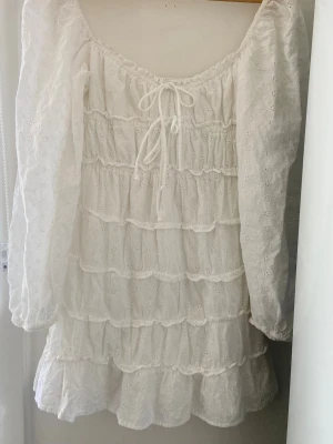 Vit mini-klänning puffärm,klockad  - Vit klänning, broderie anglaise, spets, sommarklänning, mini-klänning, puffärm, klockad kjol, snörning, sommar. Material: bomull   Storlek 32 passar en XS/S Rymligt och stretchigt material