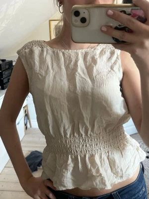 Beige blus från Kappahl - Snygg blus från Kappahl. Smockad nertill och lite utsvängd. Knappt använd, storlek S! (Skrynklig på bilden)