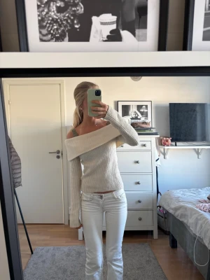 Off shoulder beige stickad tröja - Trendig beige stickad tröja med off shoulder-design och långa ärmar. Tröjan har ribbstickad struktur och bred krage som ger en snygg och avslappnad look. Perfekt att matcha med jeans eller kjol för en cool vardagsstil.