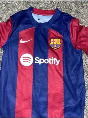 Barcelona matchtröja Nike - Säljer en Barcelona matchtröja från Nike med klassiska blå och röda vertikala ränder. Tröjan har klubbens emblem på bröstet, Nike-logga och Spotify som sponsor. Materialet är lätt och andas, perfekt för fotboll eller träning.köpt från riktiga Barcelona shoppen för 1200