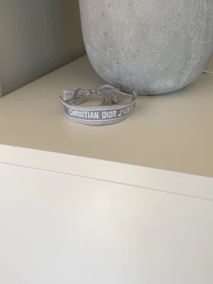 Dior armband  - Fräscht och snyggt armband i färgen grå från Dior. Sista touchen för att göra din outfit komplet!