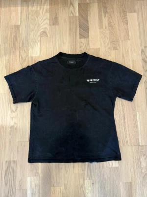 Represent t shirt - Svart t-shirt från Represent med klassisk passform och korta ärmar. T-shirten har ett diskret vitt tryck med märkesnamnet på bröstet. Materialet är mjuk bomull och modellen är enkel och stilren, perfekt för dig som gillar streetwear.