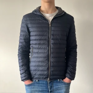 Mörkblå vår pufferjacka från Colmar - Hej! Säljer nu min jacka från märket Colmar, i storlek 48/S. bra skick utom två väldigt små hål som inte tänks på vid användning eller syns . Jackan passar perfekt nu till sommarn. Tveka inte på att höra av dig om du har några frågor eller funderingar kring jackan!