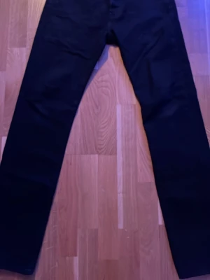 Svarta raka jeans Levi's W28 L32 - Säljer ett par klassiska svarta jeans från Levi's i modell med raka ben. Jeansen har enkel design utan slitningar och är tillverkade i ett mjukt bomullsmaterial. Perfekta för dig som gillar stilrena och tidlösa plagg.