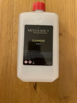 Miss Fancy Professional Cleanser 1000ml - Cleanser för naglar från Miss Fancy Professional, 1000ml. Kommer i en vit plastflaska med röd skruvkork och svart etikett. Perfekt för att rengöra och ta bort kladd från gel och akryl. Innehåller alkohol och används inom nagelvård.