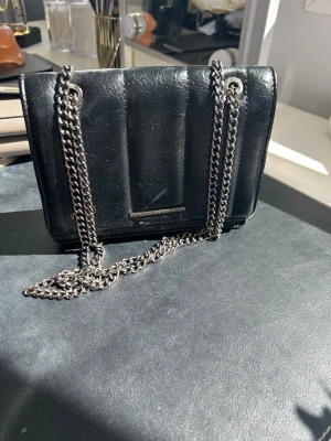Svart handväska med kedja - Svart handväska med kedja från Pull and Bear. Super fin och i mycket bra skick. Säljer pga att jag köpt en ny väska och den inte kommer till användning längre. 