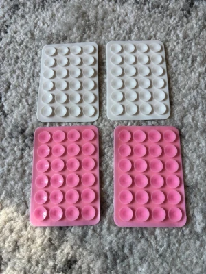 Fyra mobilgrepp Octopus pop it i silikon - 4st mobilgrepp med klister på baksidan. Säljer fyra rektangulära pop it-leksaker i silikon, två vita och två rosa. Perfekta för att stressa ner eller bara ha kul med. Varje platta har flera bubblor att trycka på och är smidiga att ta med överallt.