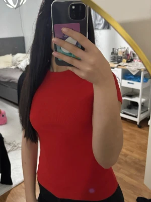 Röd ribbad kortärmad topp - En snygg röd topp med ribbad struktur och korta ärmar. Modellen är figurnära och har en enkel rund halsringning. Perfekt för att skapa en clean och stilren look.