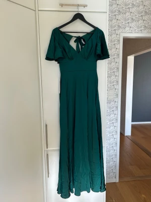 Grön balklänning med knyt i ryggen - Elegant grön långklänning med v-ringning, korta vida ärmar och snygg knytning i ryggen. 