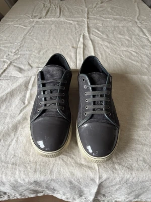 Lanvin Skor - Säljer ett par riktigt fina Lavin skor som är Storlek Uk10 vilket motsvarar ca 44,5. Skorna är i bra skick, inga skador på mockan. De har ett hål i ena skons häl men det är bara tyget de är hål i inte själva skon, märks inte eller känns inte när skorna andvänds. Frågor eller funderingar är det bara att höra av sig!