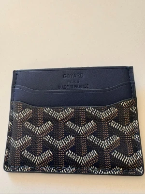 Mörk blå korthållare - Snygg mörkblå korthållaremed klassiskt mönster i blått vitt och beige. Tillverkat i läder med flera kortfack och präglad logotyp på framsidan. Perfekt för dig som vill ha en stilren och exklusiv accessoar i fickan.pris kan diskuteras vid snabb äffär!