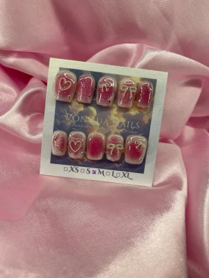 SugarBling (M);Short Ballerina - Snygga handgjorda press-on naglar i rosa blush ombre med silvriga detaljer som hjärtan, rosetter och cateye/glitter. Naglarna har en kort, ballerina form och är dekorerade med små stenar för extra bling. Perfekt för dig som vill ha en söt och unik nagelstil. M: 16 mm, 12 mm, 12,5 mm, 11,5 mm, 10 mm