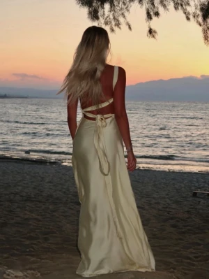 Gul satinbalklänning med knytningar  - Från: bystina och den är i storlek xs/s. Köpt på vinted, endast använd en gång av tidigare ägare & av mig endast testad. Den är lite nopprig och kan ha små fläckar speciellt vid släpet men inget man lägger märke till. Orginalpriset är 1600