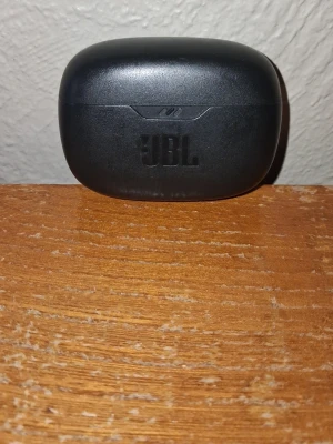 JBL svarta trådlösa in-ear hörlurar - Snygga svarta trådlösa in-ear hörlurar från JBL med laddningsetui i matt plast. Perfekta för musik, poddar och samtal på språng. Smidig och kompakt design som är lätt att ta med sig överallt.