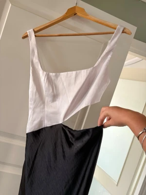 Svartvit långklänning från meskhi  - Snygg svartvit långklänning från meshki med halvöppen midja. Klänningen har breda axelband och är figurnära upptill. Perfekt för speciella tillställningar, jag har haft den vid enstaka tillfällen som dop, bröllop och examensfest. Tyvärr passar den mig inte längre…