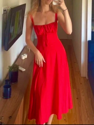 Röd långklänning med smala axelband, S - Säljer en röd långklänning med smala axelband och markerad midja, storlek S. Klänningen har en feminin siluett och ett flytande fall som ger en romantisk vibe. Perfekt för sommarens alla tillfällen. Materialet känns lätt och svalt.