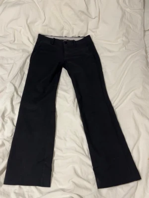 Lågmidjade kostymbyxor - Säljer då jag har ett annat par och inte behöver två. De är lite smått skrynkliga längst ner i benen(se sista bilden). Annars är de gott skick. Rollar de innan jag skickar dem. Midjemått rakt över är ca 37. Innerbenslängd är 74 cm. Grenhöjd 22 cm. 