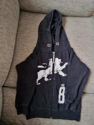 Huvtröja med dragkedja - Snöret till huvan är borta och färgen är något urtvättad, det syns bland annat på sömmarna (se bild). Stl 100 