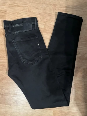 Replay Anbass Hyperflex Jeans Svarta W30/L34 - Mycket fint skick. Storlek W30/L34. Mått - Midja: 42cm, Ytterbenslängd: 109,5cm, Benöppning: 15cm.