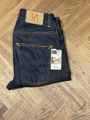 Mörkblå jeans från Nudie Jeans - Säljer ett dessa raw denim jeans från Nudie det är andvända en gång har kvar lappen som satt på de från början modellen loose Leif sitter rätt så straight på aldrig tvättade så de är redo att andvändas av någon annan och få feta fades 