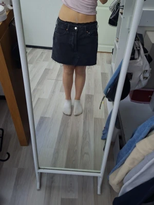 Svart kort jeanskjol med fickor - Säljer en svart kort jeanskjol med klassiska fickor fram och bak. Perfekt för dig som gillar en enkel och stilren look. Aldrig använd.