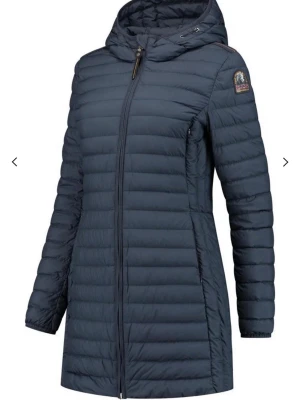 Mörkblå lång dunjacka Parajumpers - Snygg mörkblå dunjacka från Parajumpers med längre passform och huva. Jackan har quiltad design, dragkedja framtill och logotyp på ärmen. Perfekt för kalla vinterdagar och tillverkad i lätt, isolerande material. Pris kan diskuteras